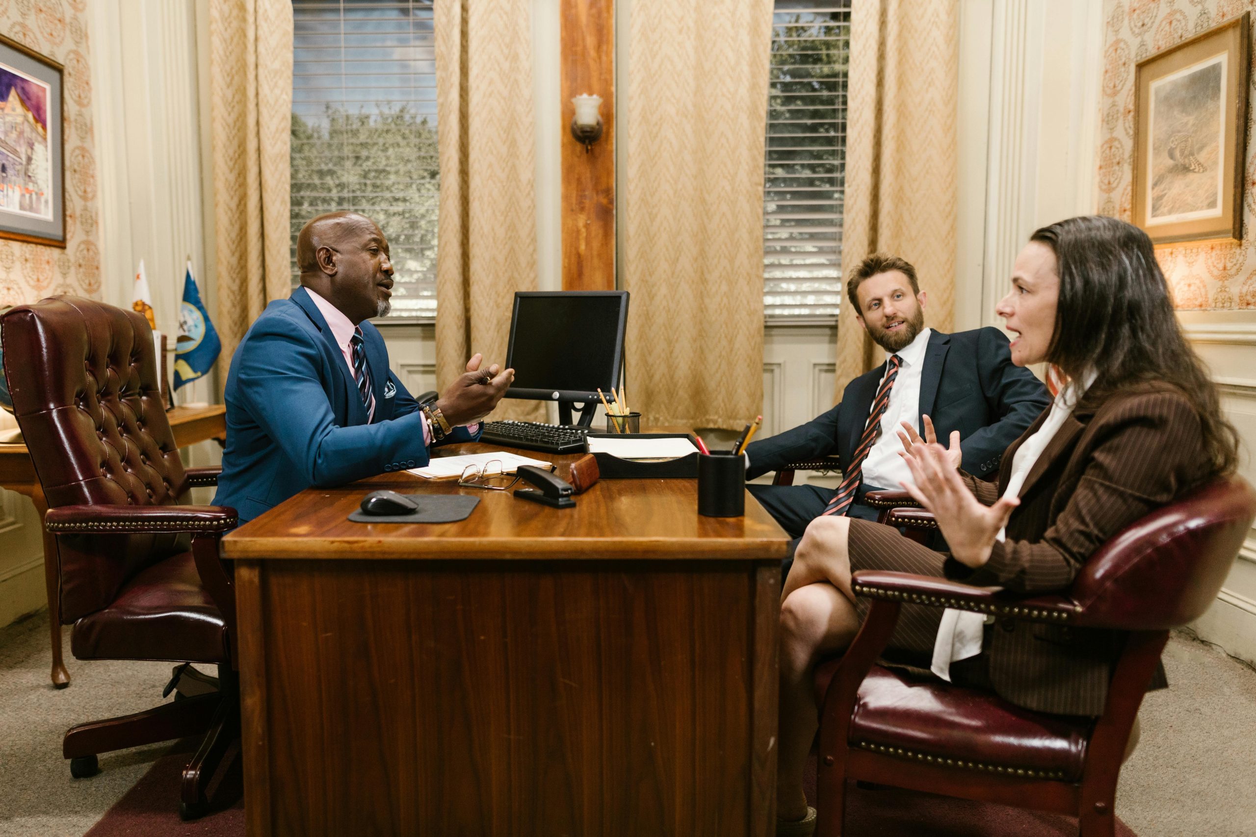 Three attorneys in a legal discussion at a well-appointed law office.