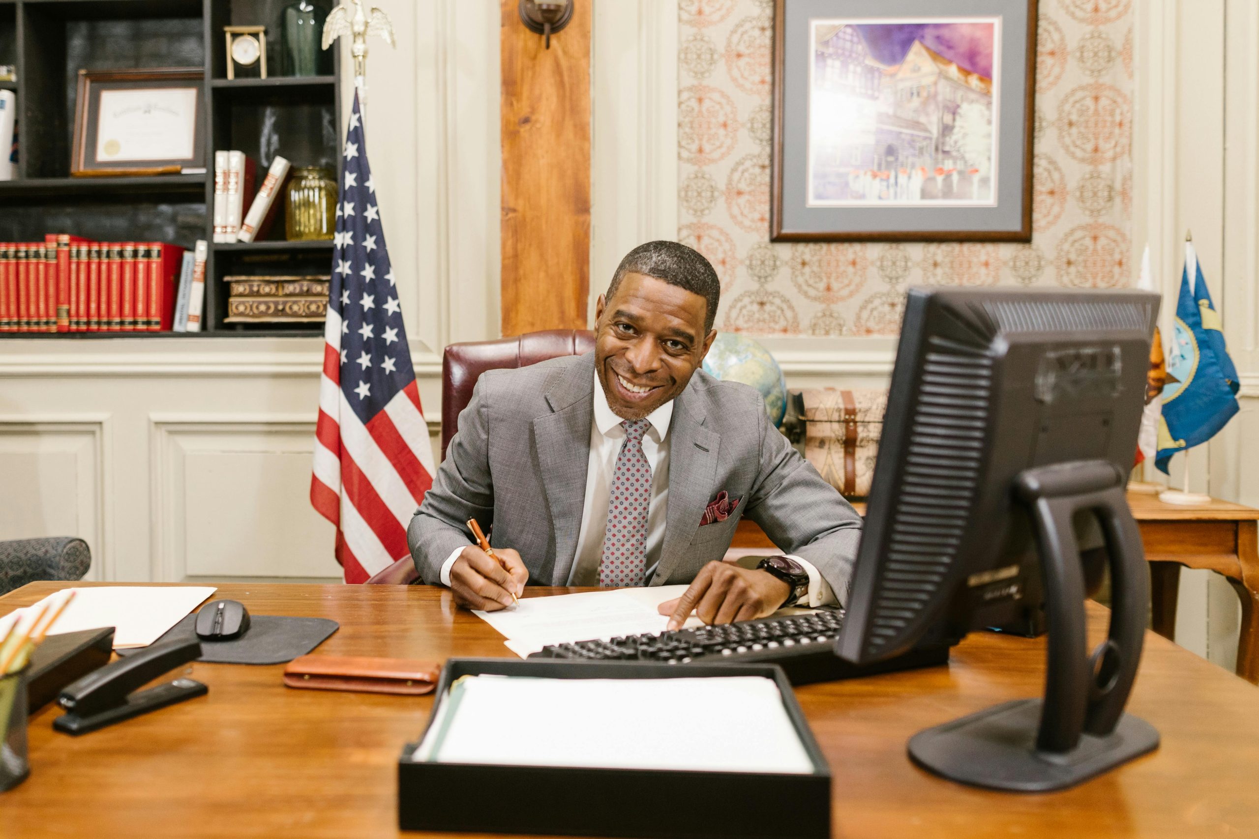 A lawyer in corporate attire smiling at a desk in a law office, displaying professionalism.