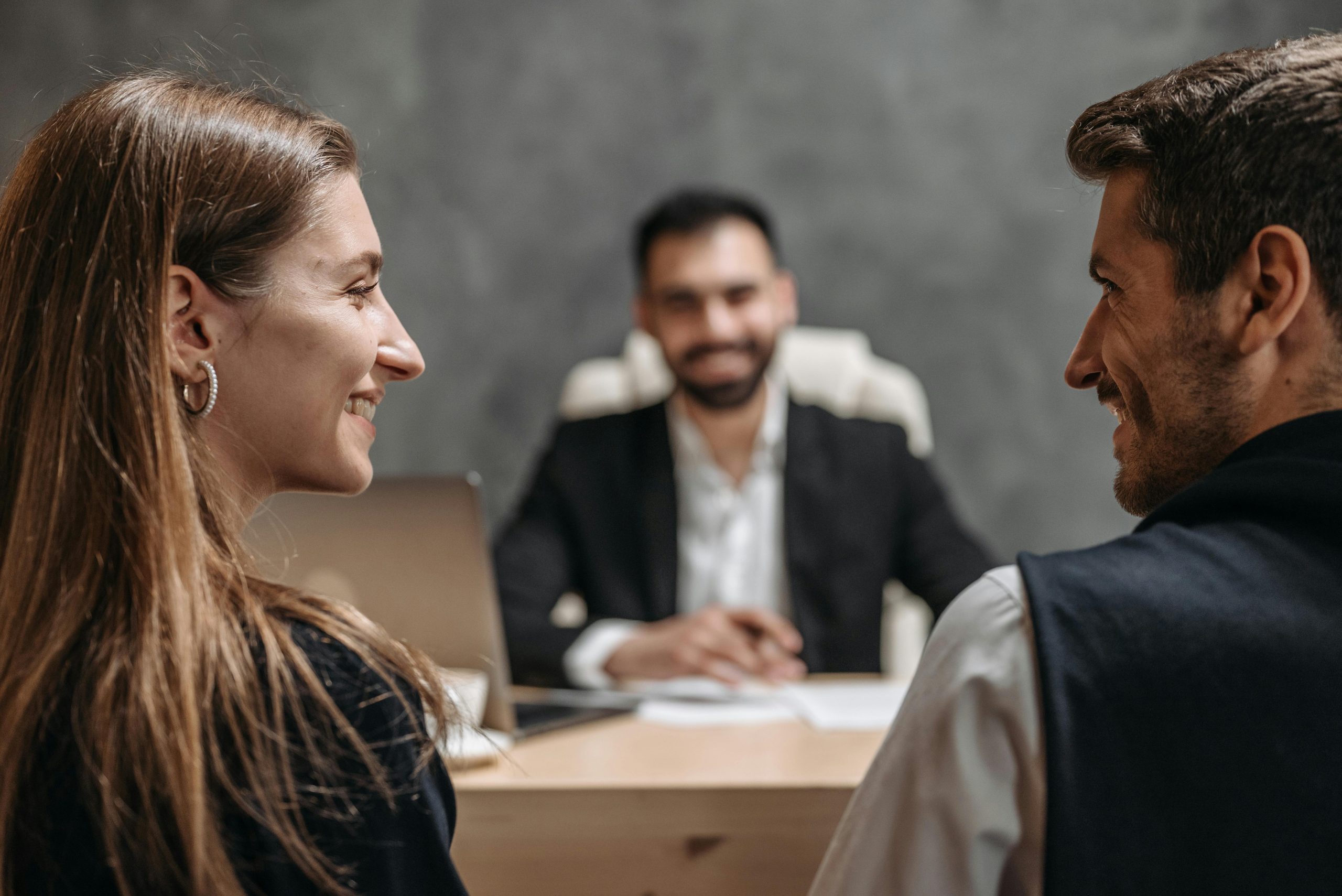 A friendly business meeting with smiling professionals seated in an office setting.